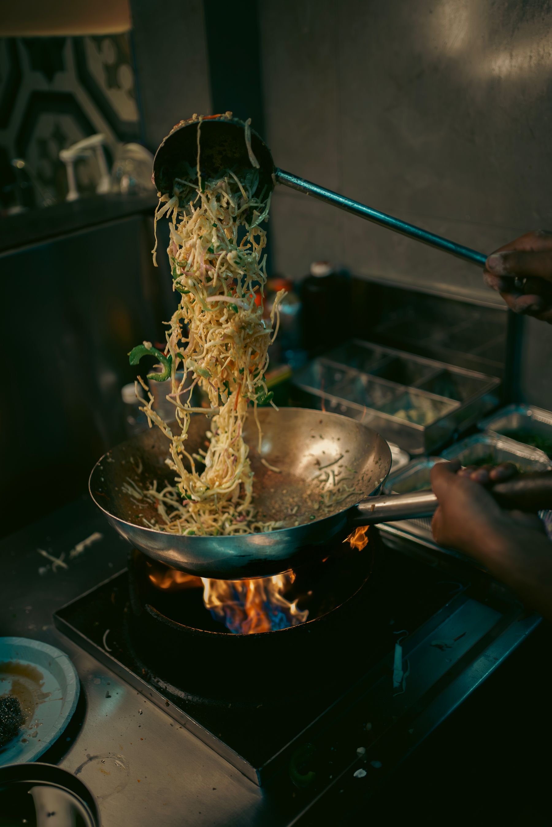 Chef tossing noodles in a flaming wok